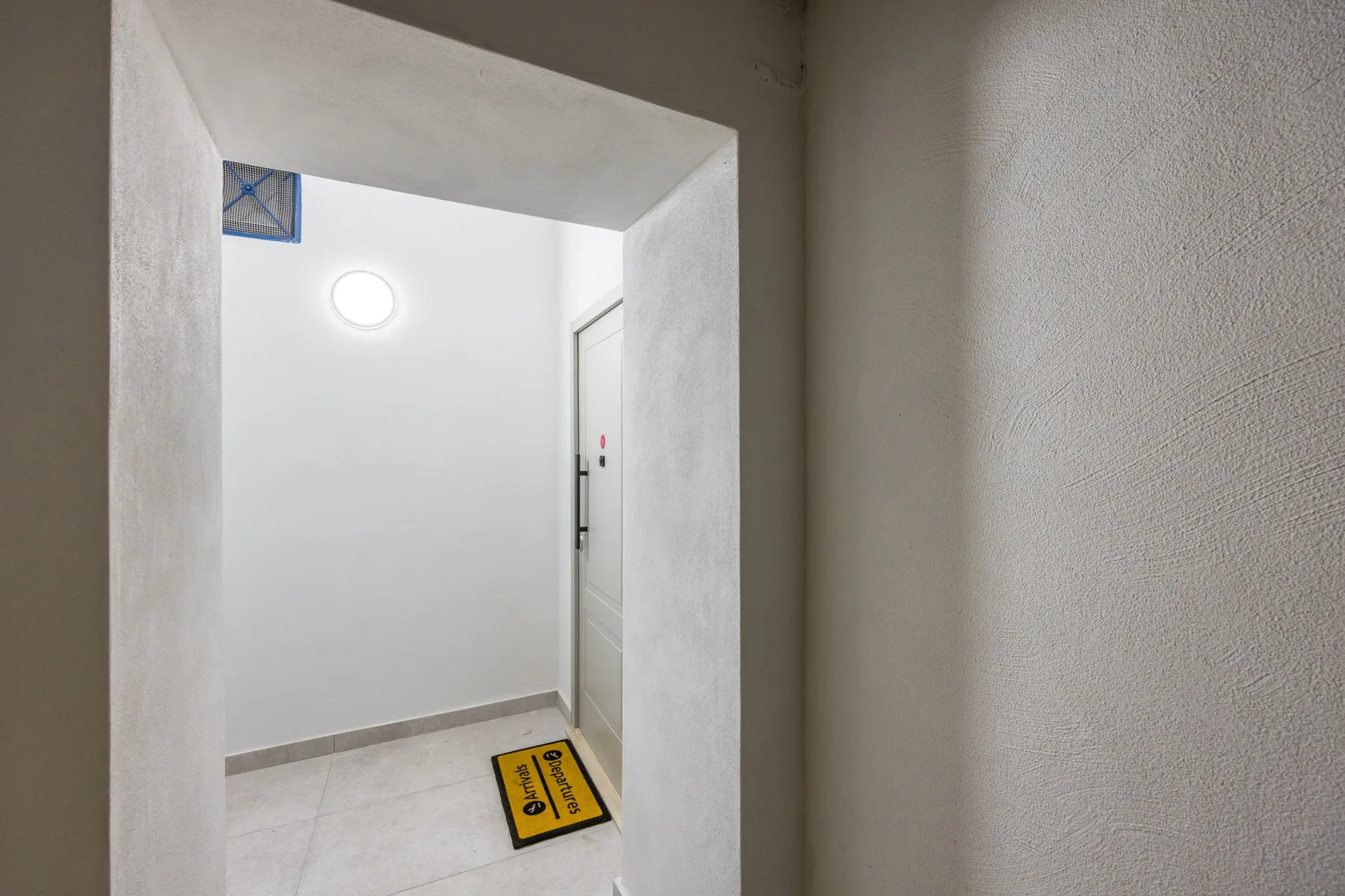 Un pequeño recibidor con una puerta blanca y una luz encima.