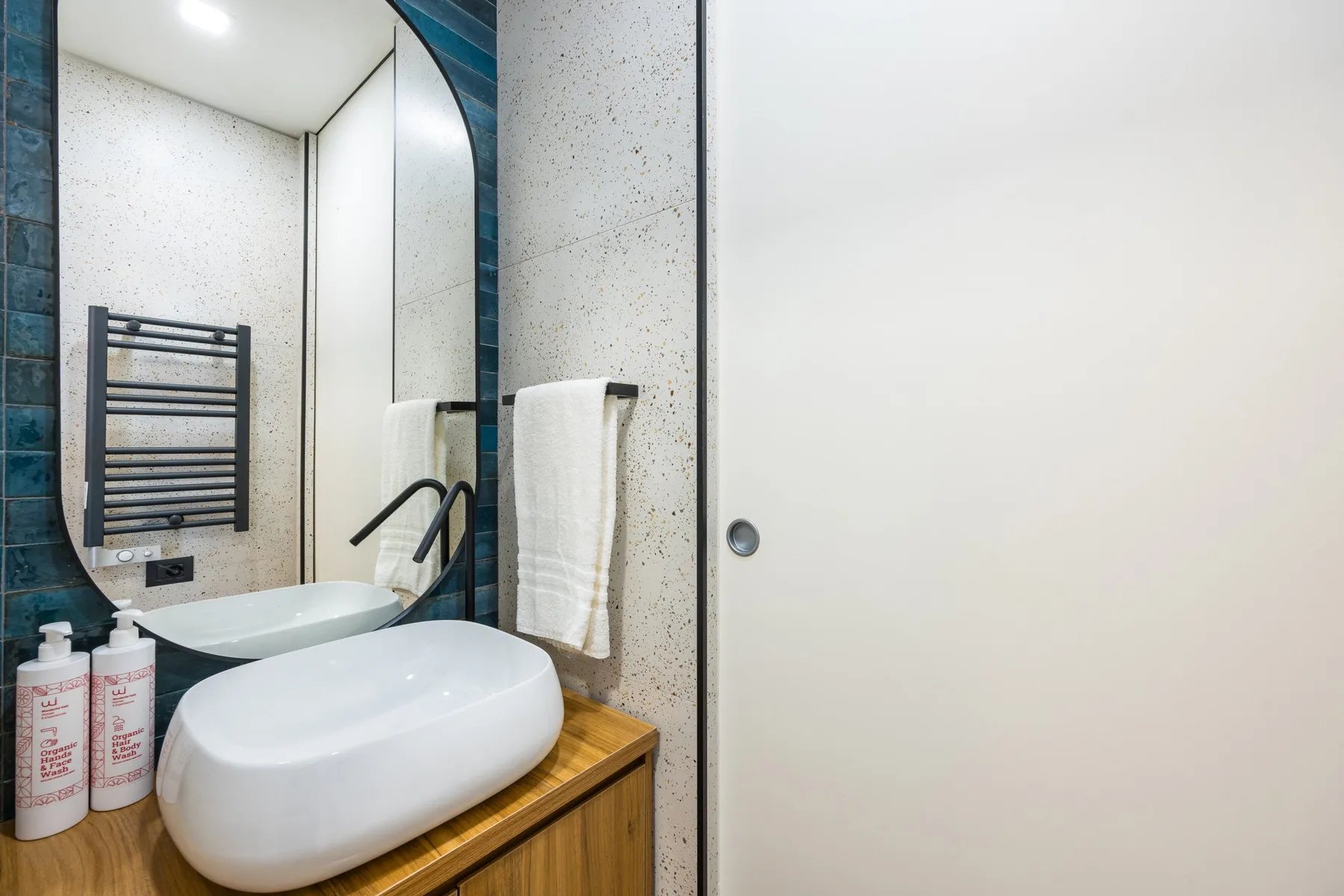 Un lavabo de baño con una pila blanca y una toalla junto a una ducha.
