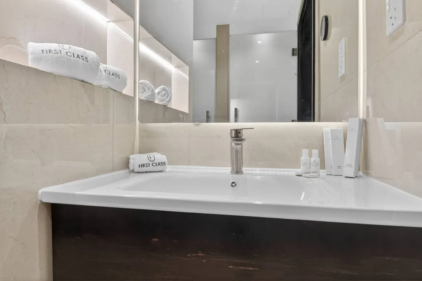Un lavabo de baño con fregadero blanco, grifo cromado y espejo de pared.