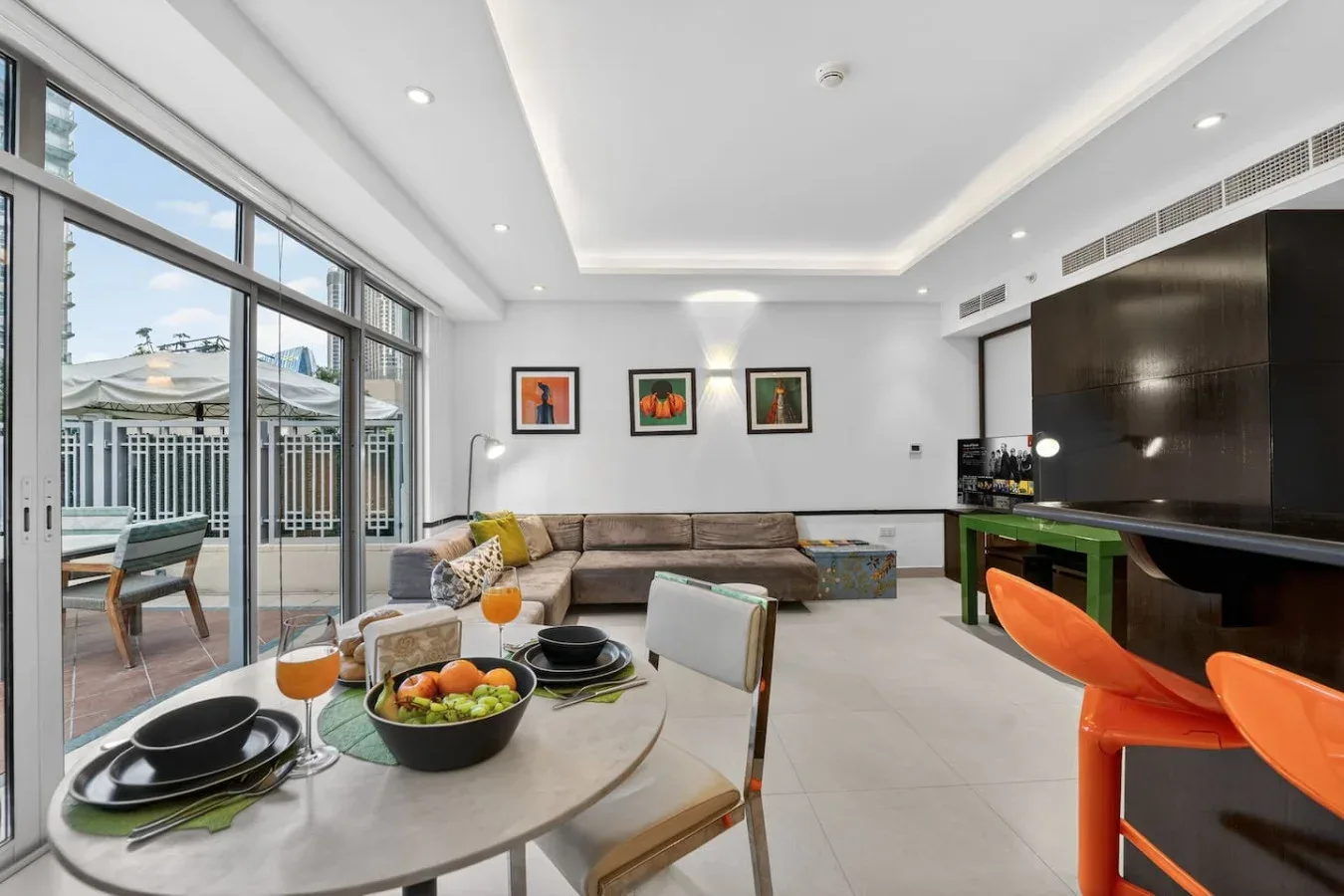 Una luminosa sala de estar y comedor con grandes ventanales y una mesa preparada para comer.