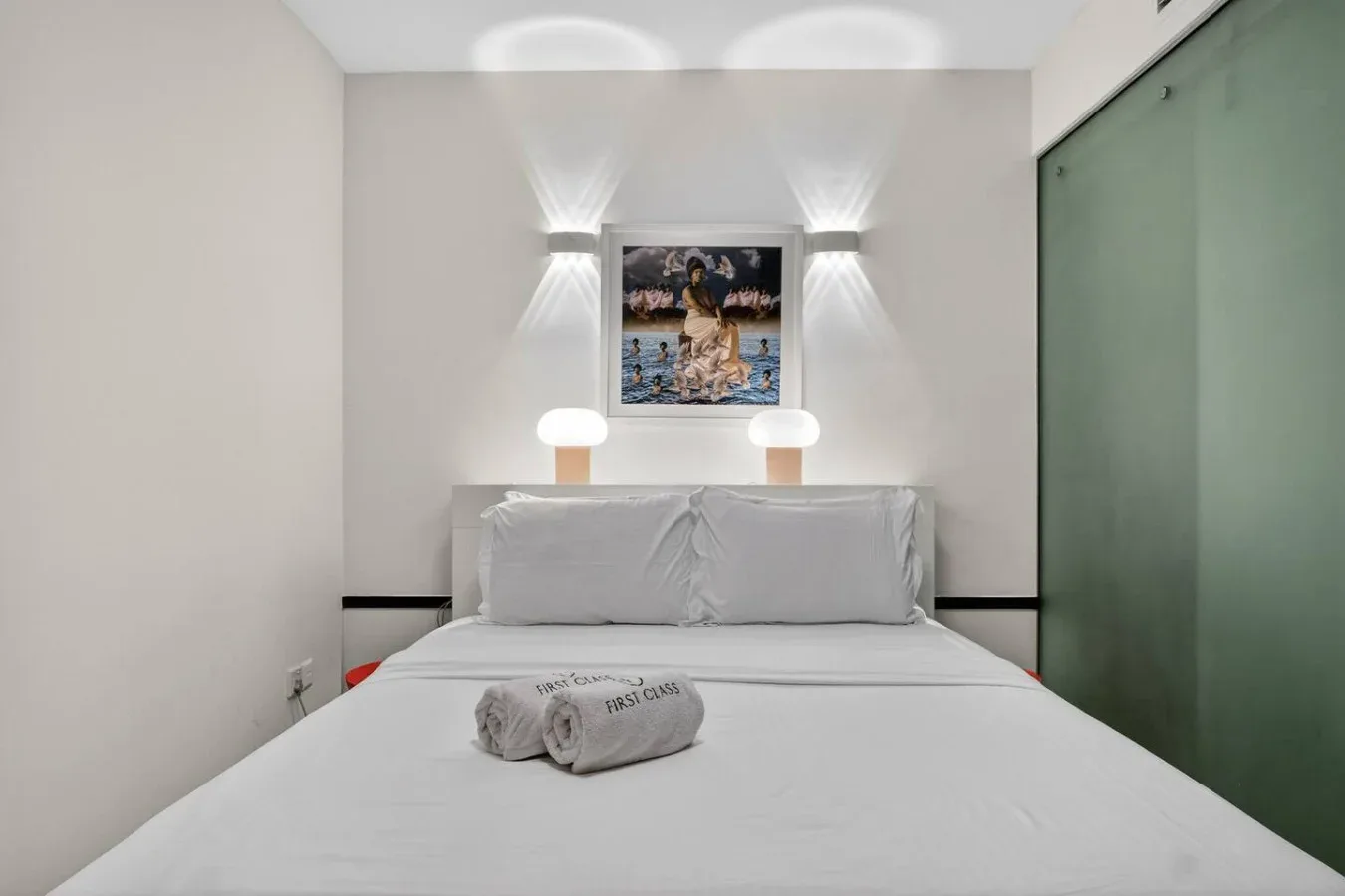 Un dormitorio con una cama bien tendida y un cuadro enmarcado encima.