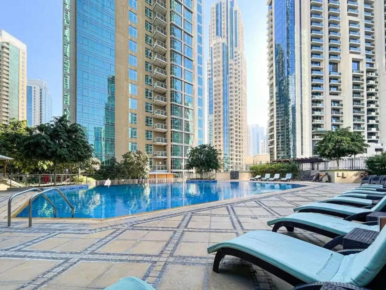 Una piscina al aire libre y asientos de descanso están rodeados de edificios altos.