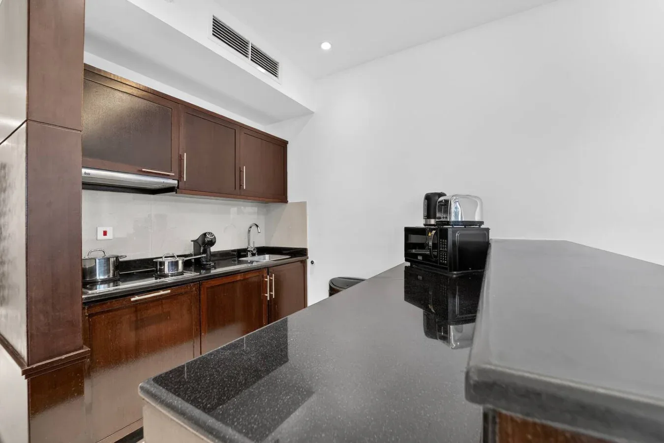 Una cocina moderna con gabinetes oscuros, fregadero y una amplia encimera.