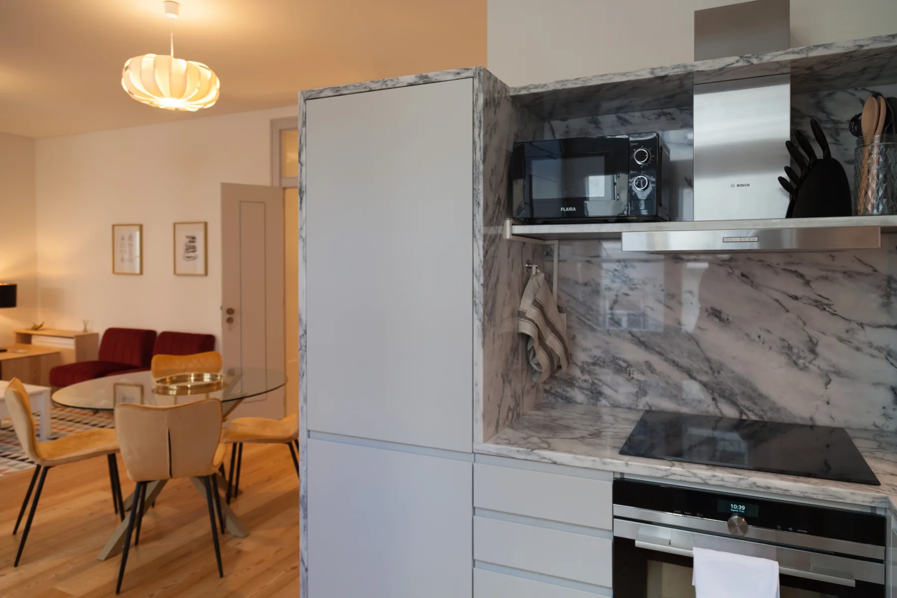 An open kitchen and dining area with a glass table and built-in appliances.