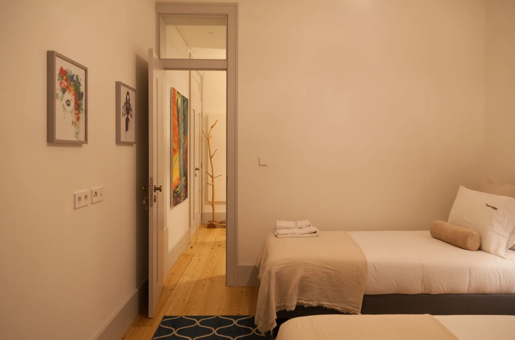 A bedroom with a neatly made bed and framed artwork on the wall.