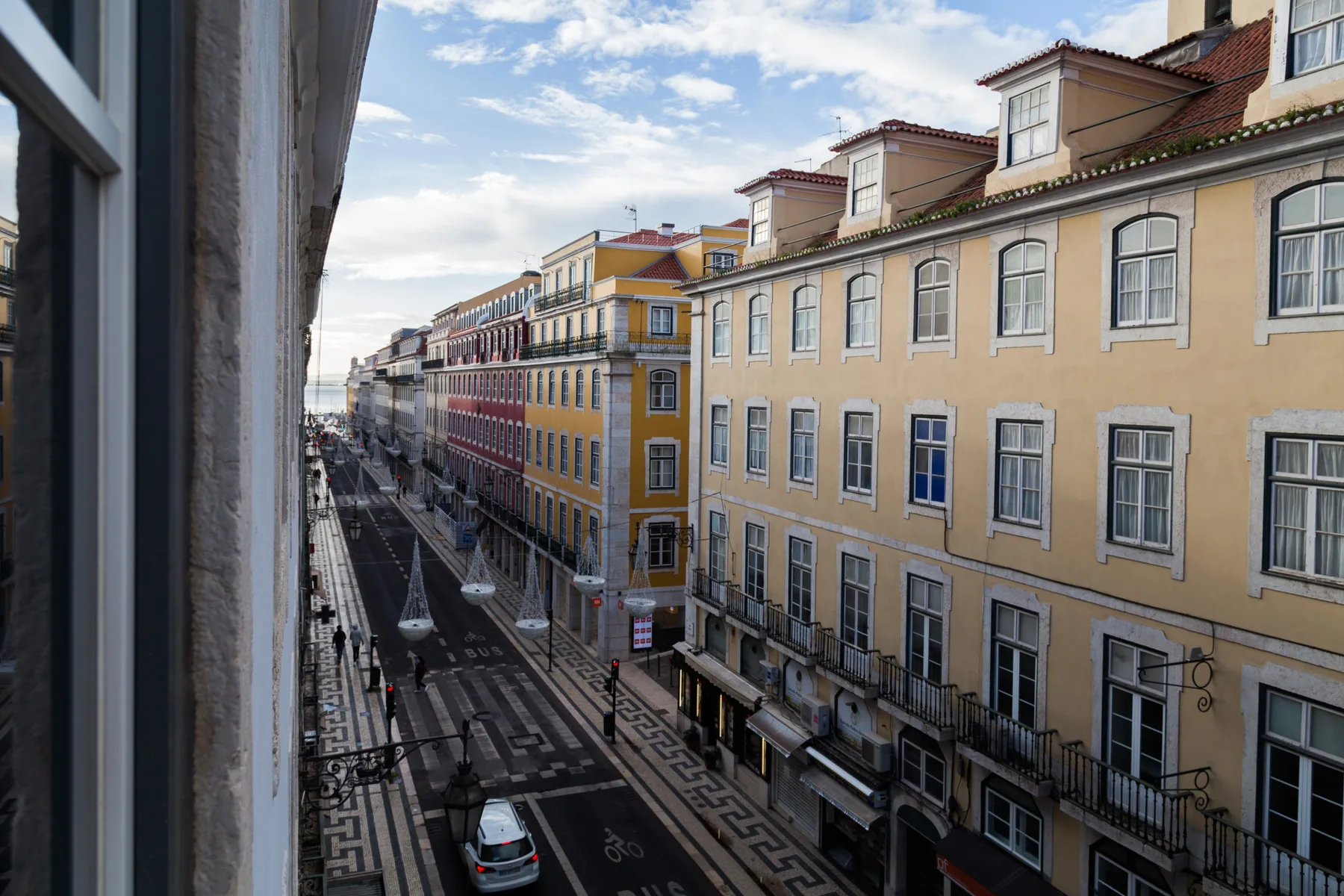 Street view of colorful buildings along a narrow urban road.