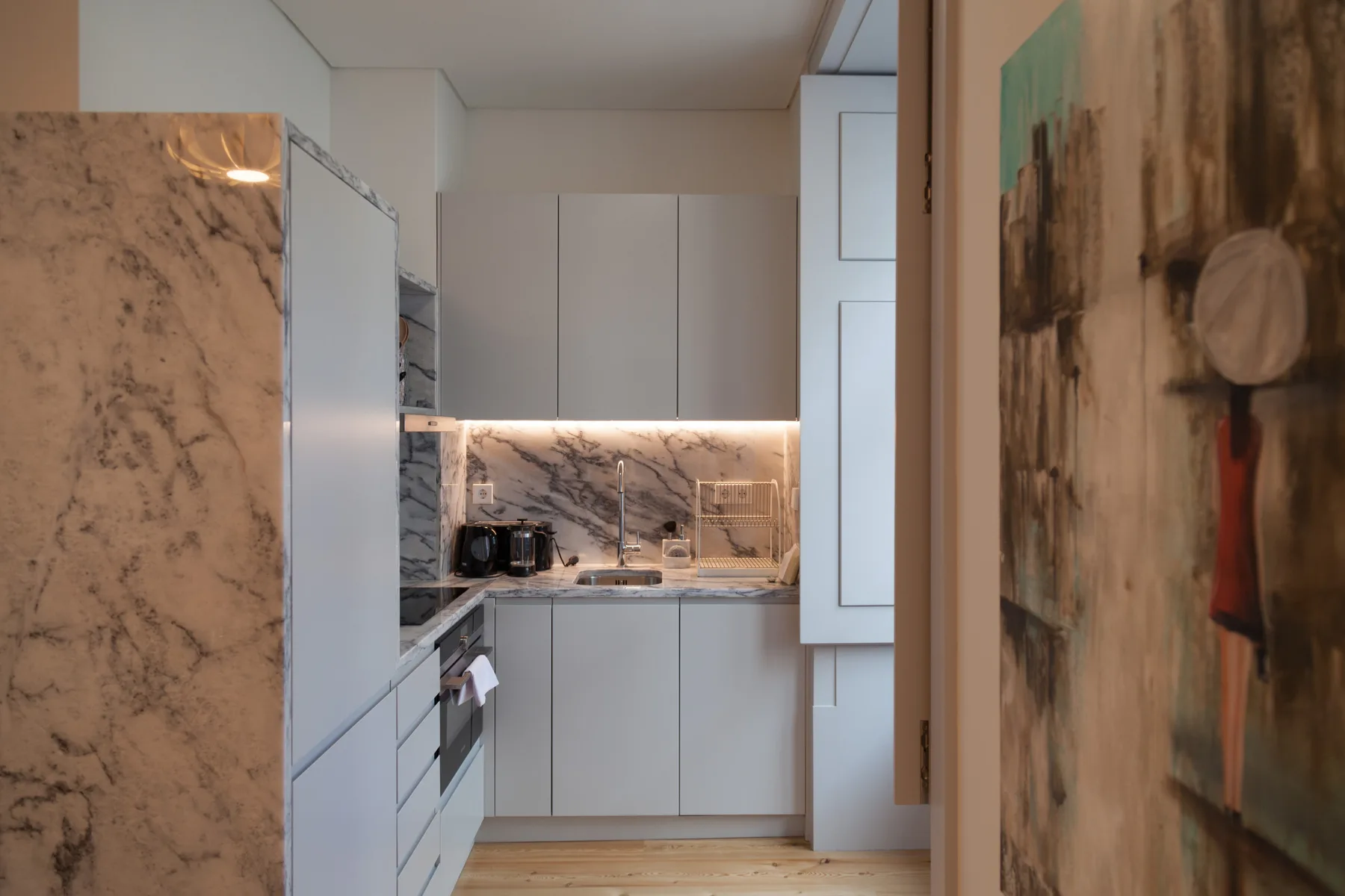 A compact kitchen with light cabinets and a marble-patterned backsplash.