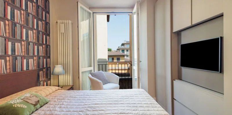 A bedroom with a bed, seating, and an open balcony door.