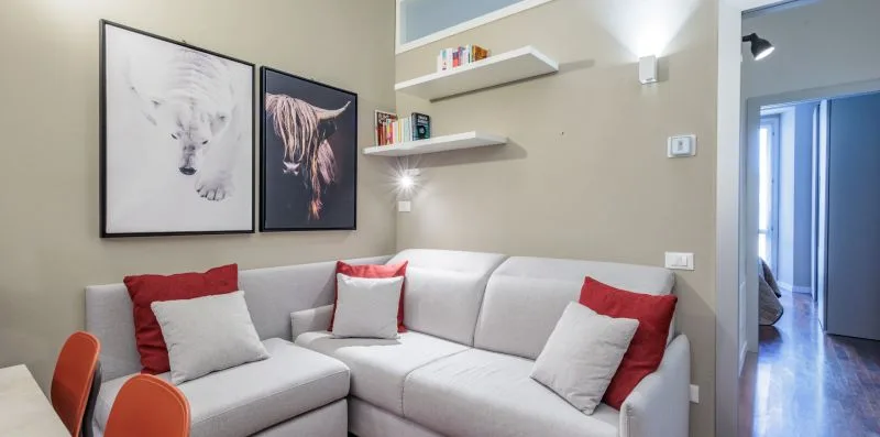 A living room with a light-colored sectional sofa and framed artwork.