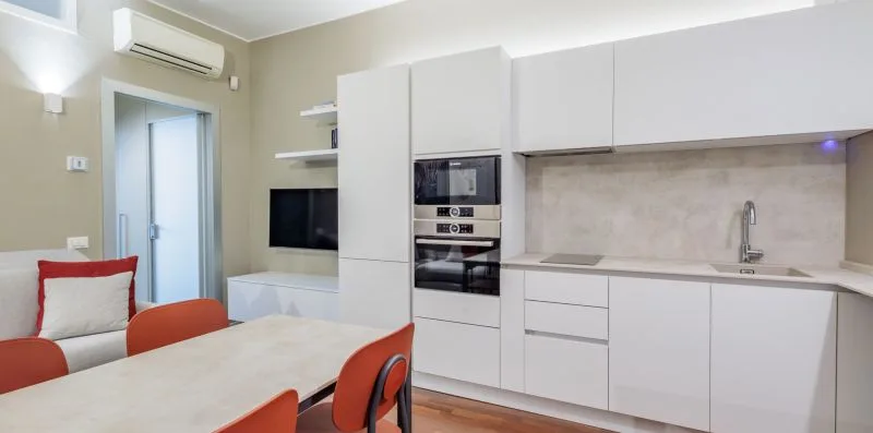 A bright kitchen with white cabinets and a dining table in the foreground.