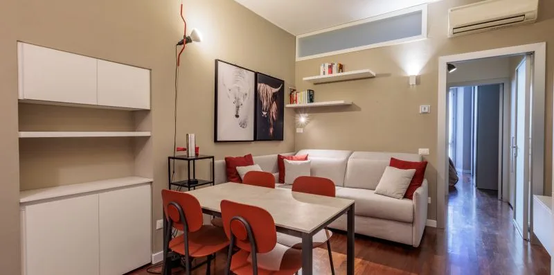A living room with a light-colored sofa and a dining table.
