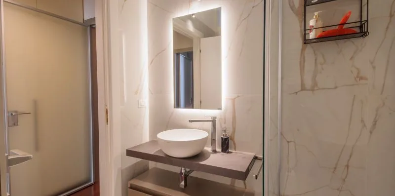 Un lavabo de baño con un lavabo sobre encimera y un espejo iluminado.