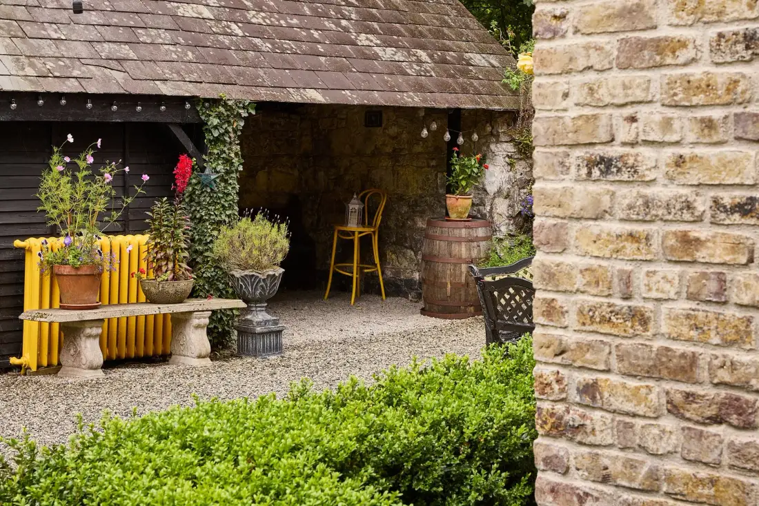 Garden seating beside a brick wall and greenery.