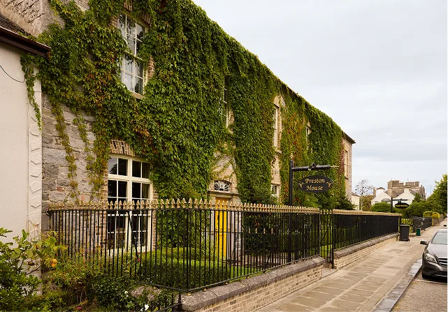 Ivy-covered stone exterior of Preston House behind an iron fence.