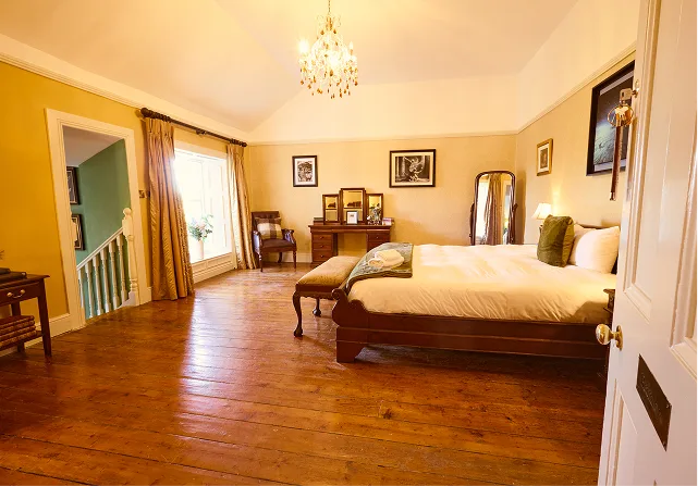 Bedroom with a large bed, wooden floor and traditional furnishings.