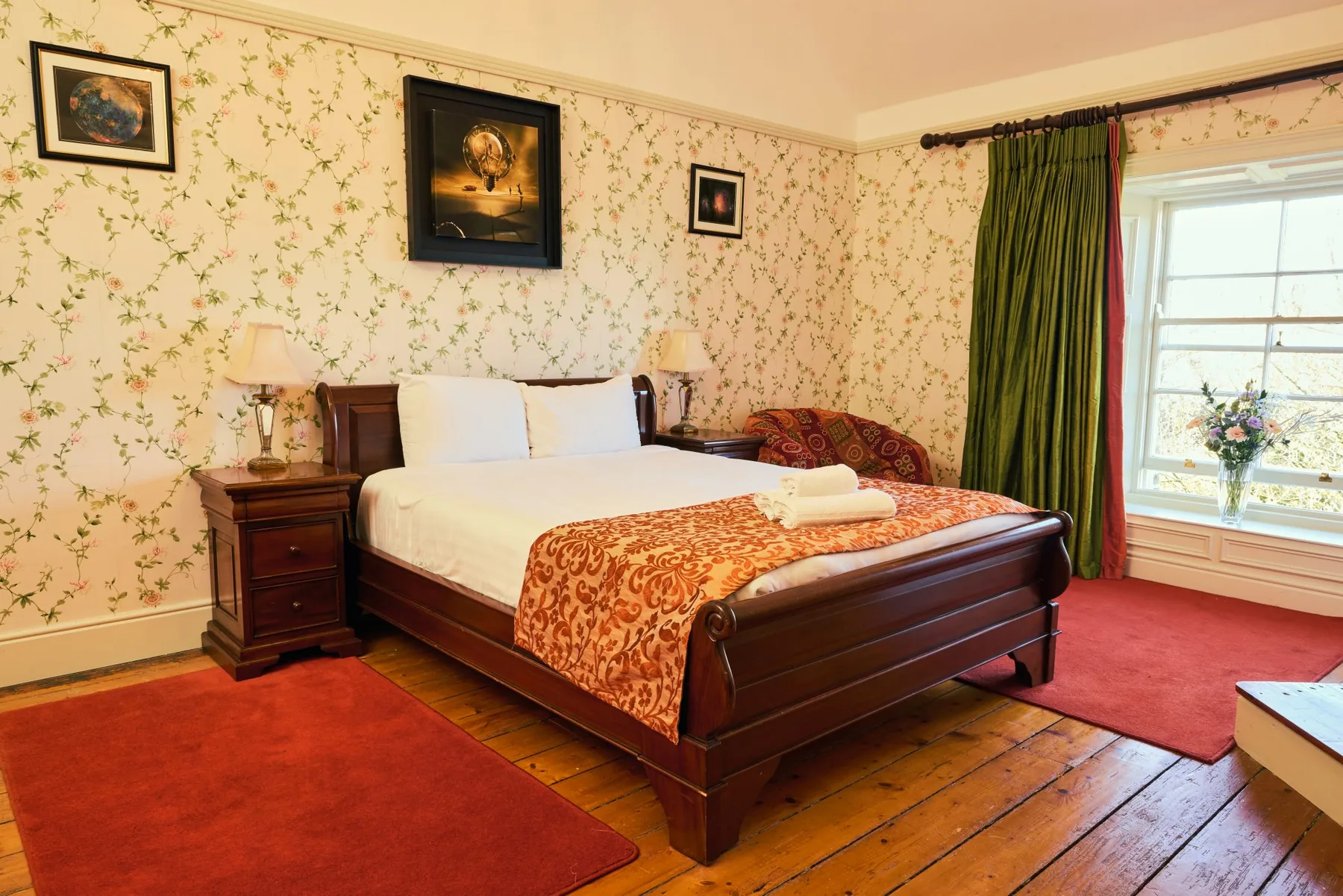 Bedroom with a wooden bed, floral wallpaper and bedside tables.