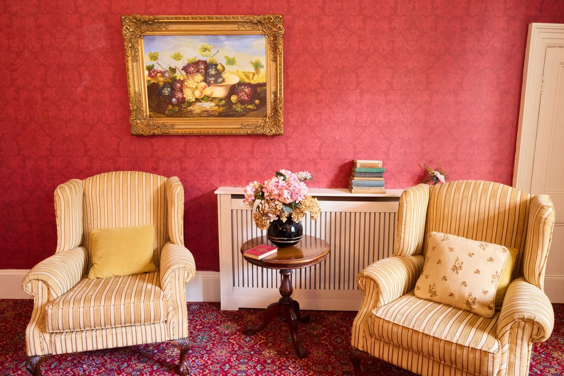 Two striped armchairs and a small table in a room with patterned wallpaper.