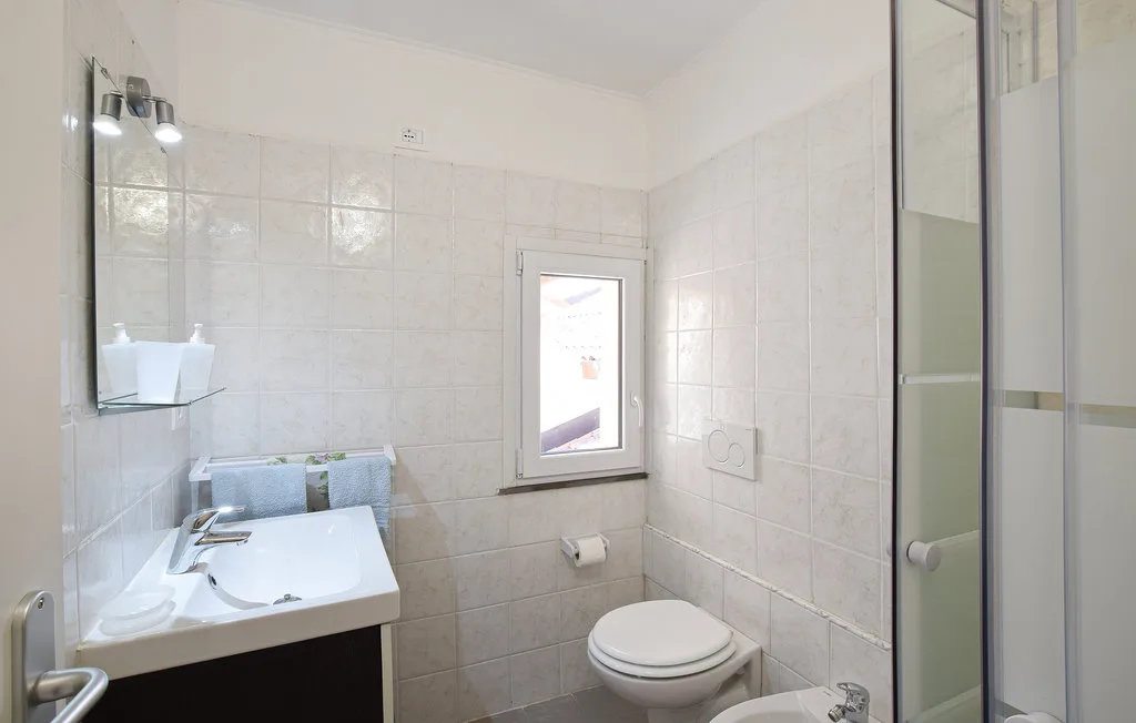 A tiled bathroom with a sink, toilet, and glass shower.