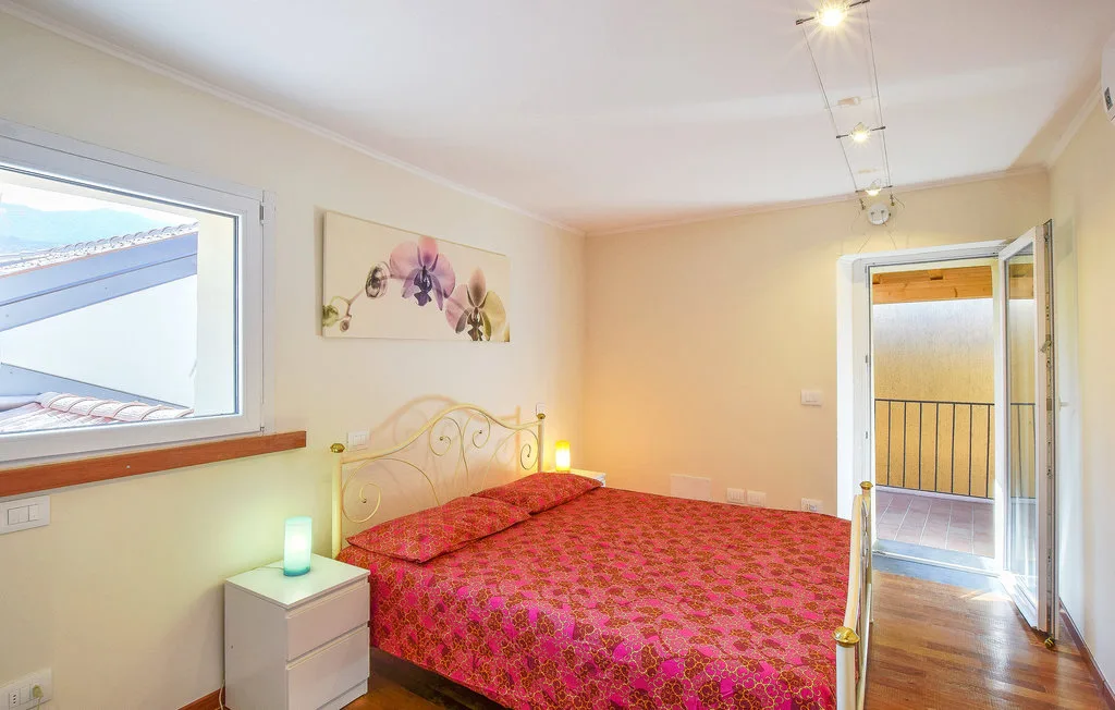 Un dormitorio con una cama cubierta con una colcha roja estampada y una ventana.