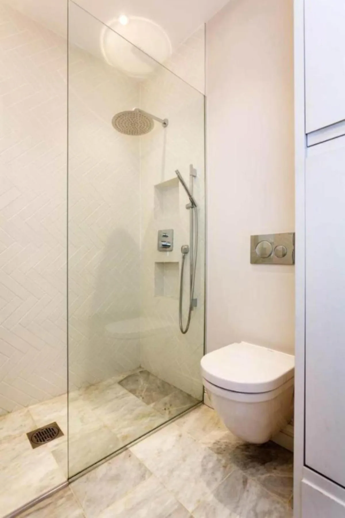 Un baño moderno con ducha de cristal y un inodoro suspendido.