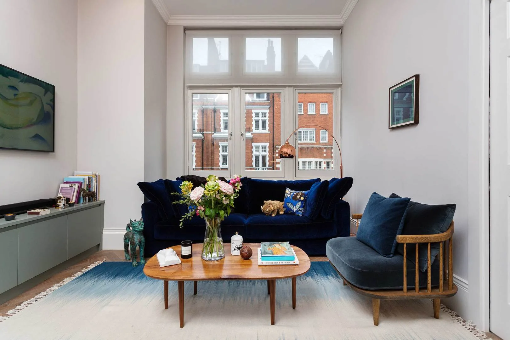 Una sala luminosa con asientos azul oscuro alrededor de una mesa de centro de madera.