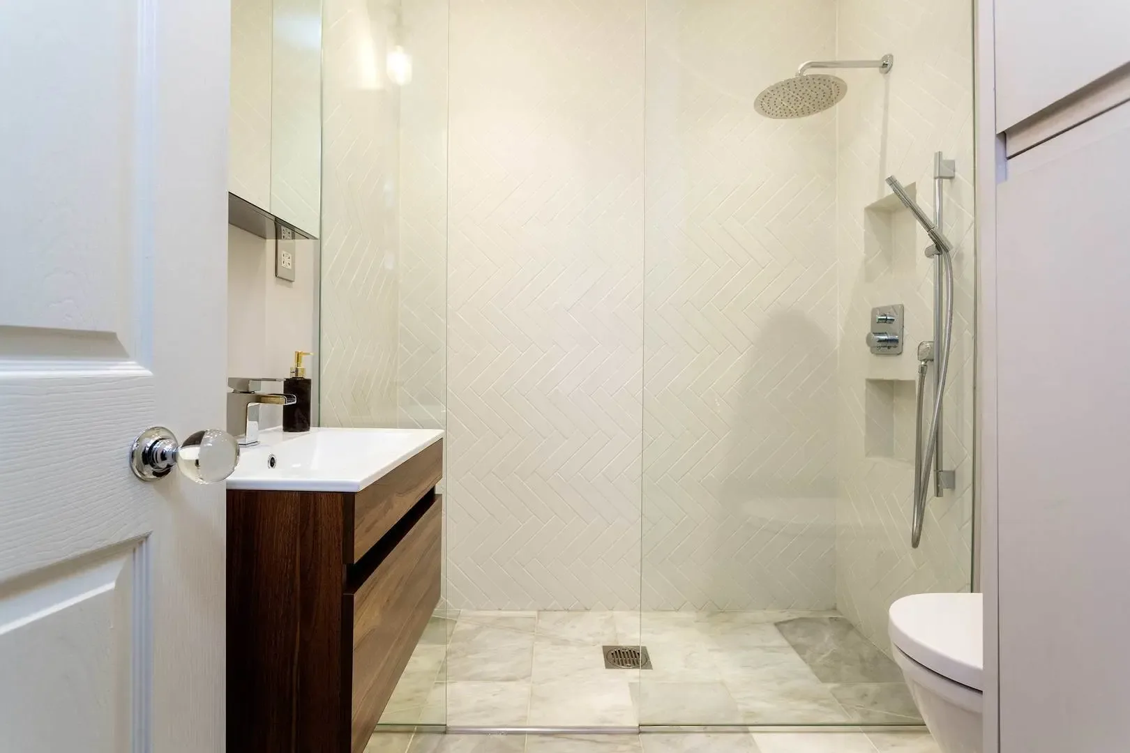 Un baño luminoso con lavabo y una ducha de mampara de vidrio.