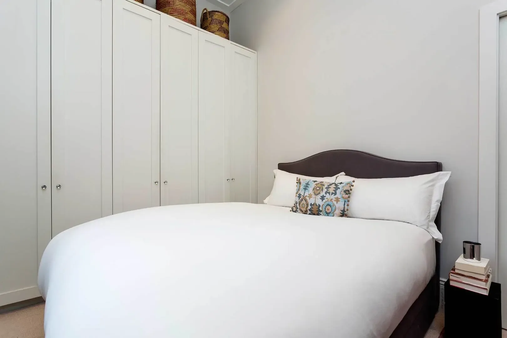 Un dormitorio con una cama bien hecha y armarios empotrados.