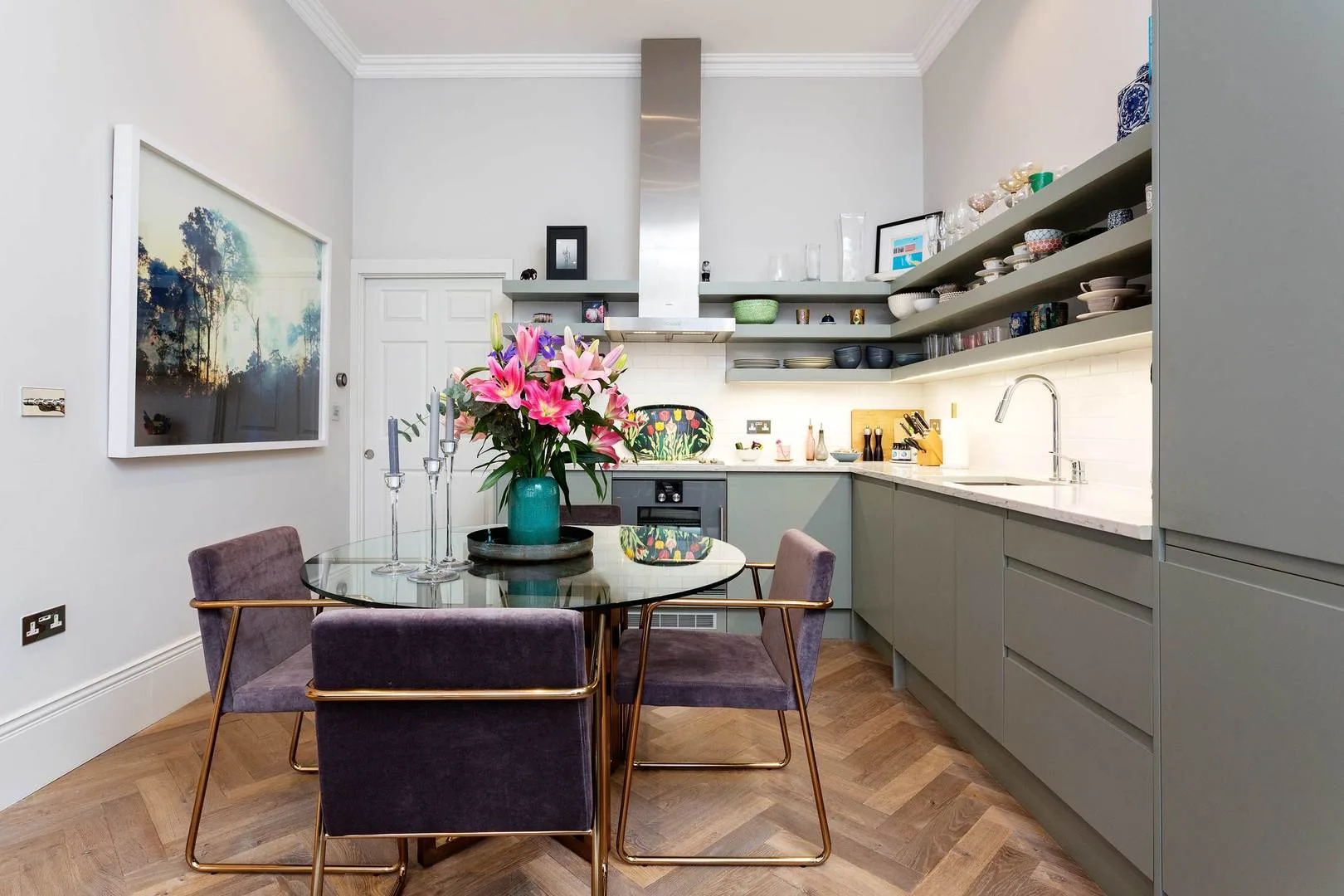 Una cocina moderna con una mesa de comedor de vidrio y flores coloridas.