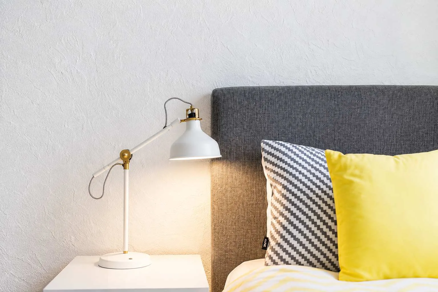 Un dormitorio con una lámpara de noche y almohadas sobre la cama.