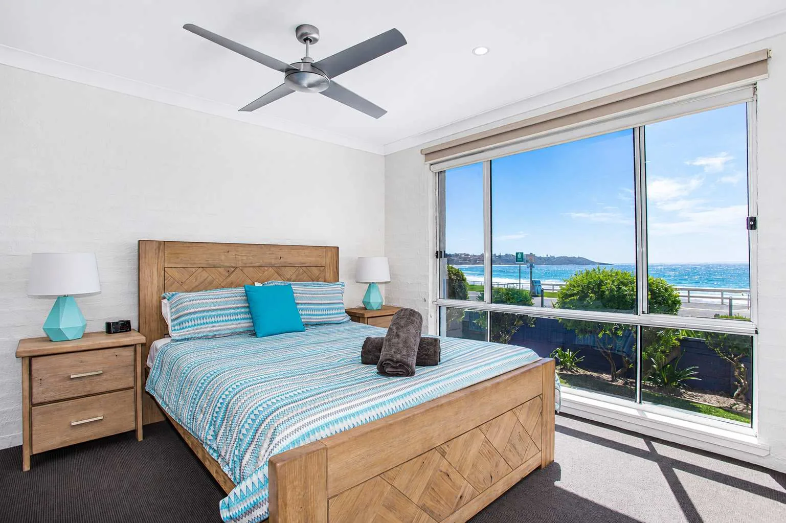 Un dormitorio con una cama de madera y una gran ventana con vistas al agua.