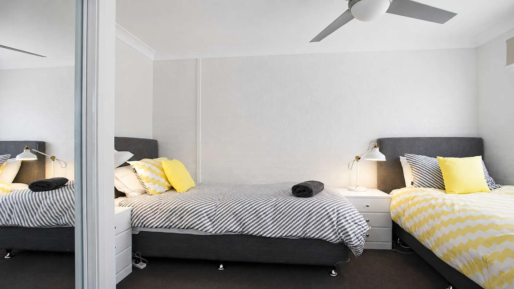 Un dormitorio con dos camas, ropa de cama a rayas y detalles amarillos.
