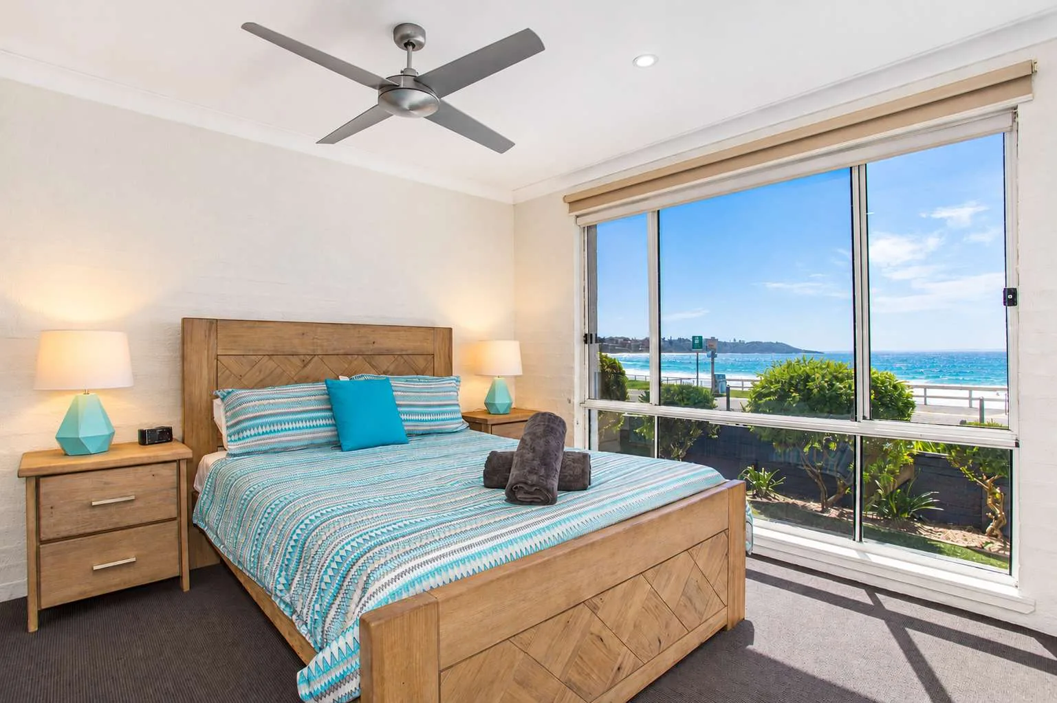 Un dormitorio con una cama grande junto a ventanas corredizas con vista al mar.