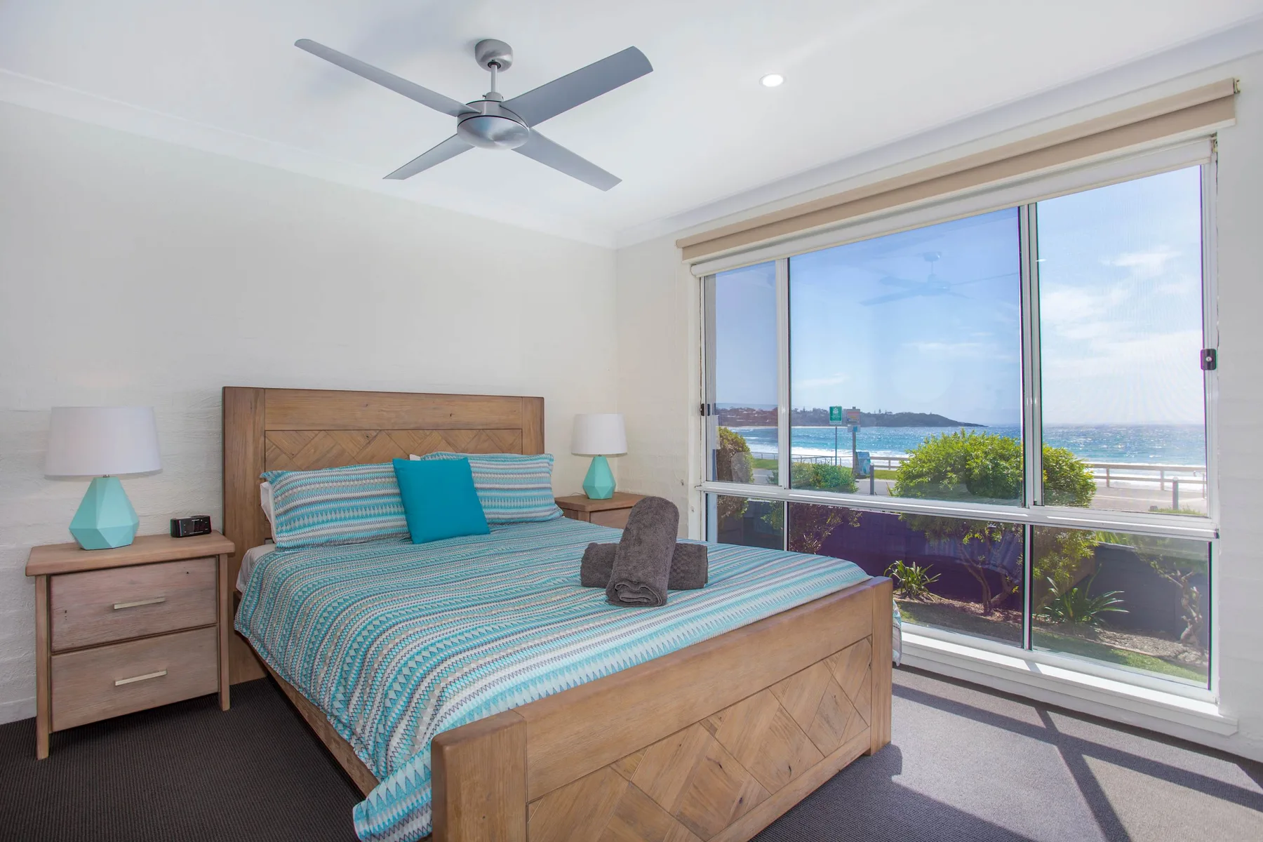 Un dormitorio con una cama junto a una ventana grande con vistas al agua.