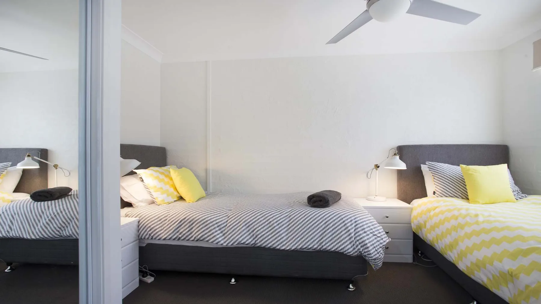Un dormitorio con dos camas, ropa de cama estampada y un ventilador de techo.
