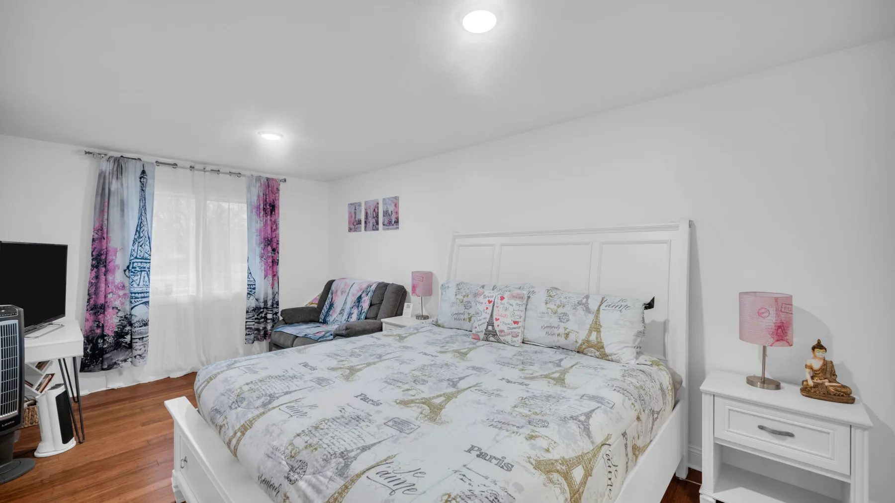 Un dormitorio con una cama grande, un pequeño sofá y una ventana con cortinas.