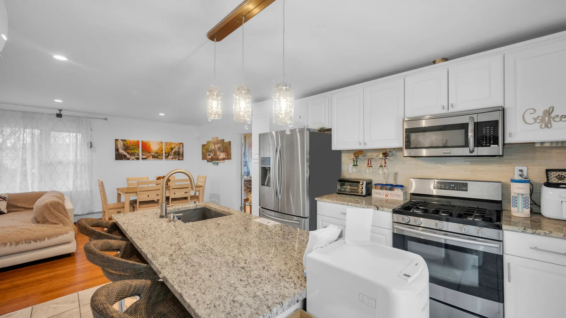 Una cocina luminosa abierta a la sala, con una isla grande y electrodomésticos de acero inoxidable.