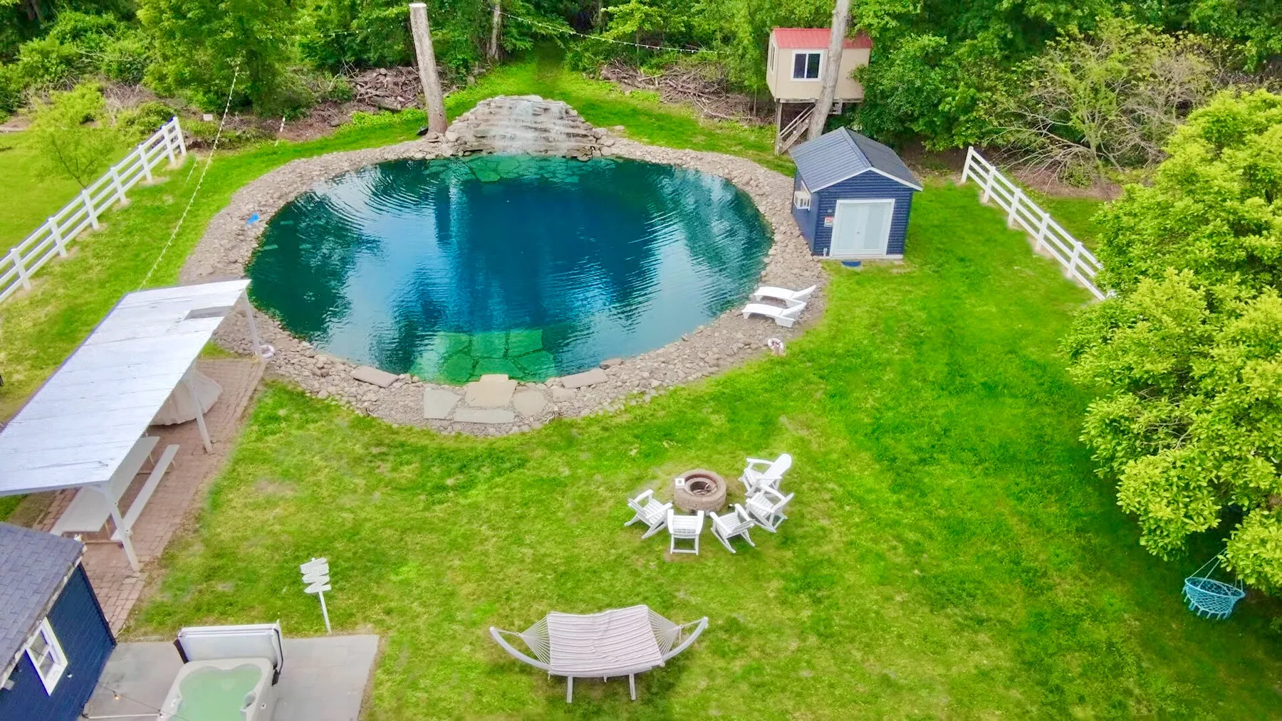 Una zona de piscina al aire libre con césped y asientos alrededor.