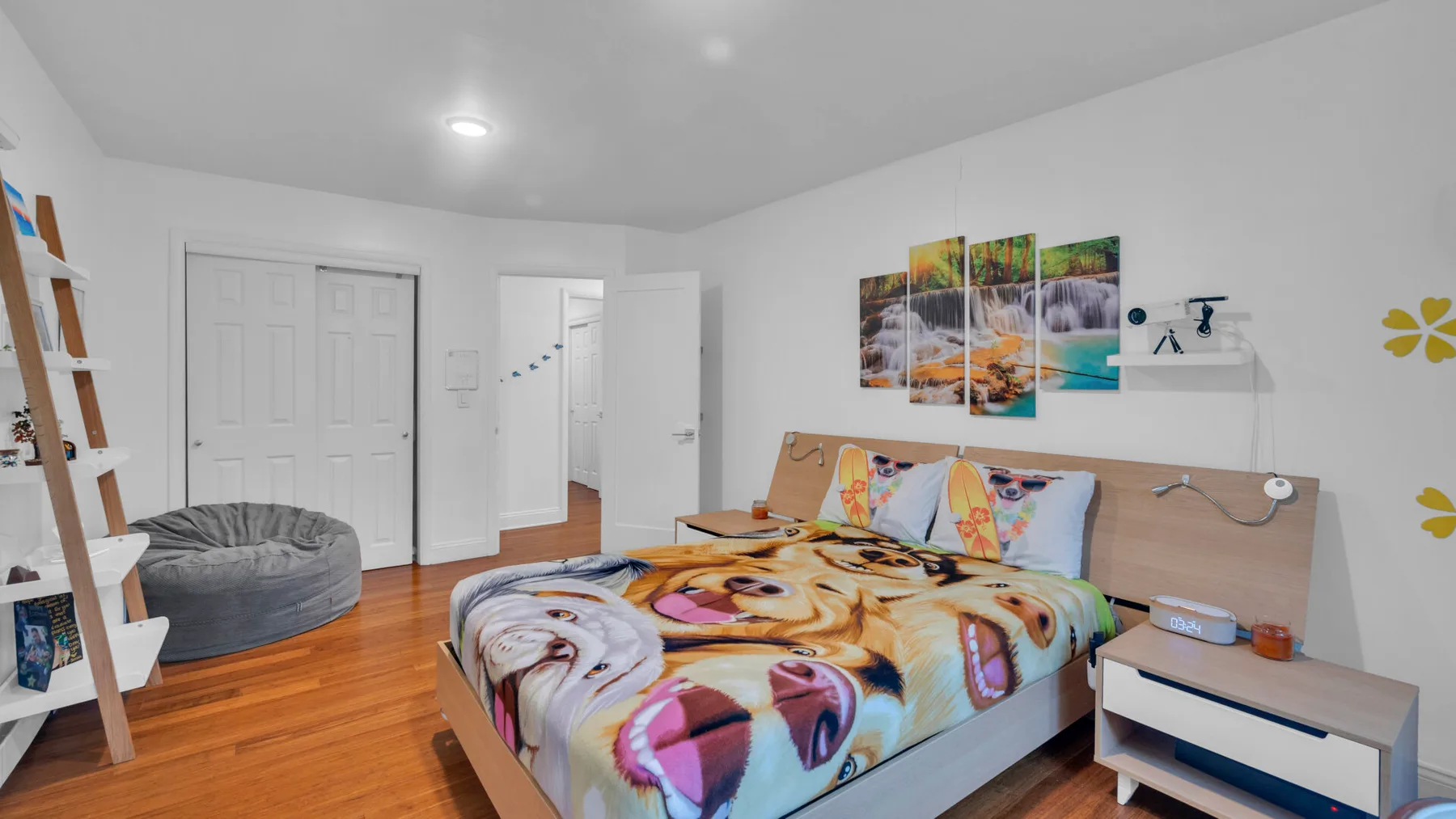 Un dormitorio con una colcha colorida, cuadros en la pared y una mesita auxiliar.