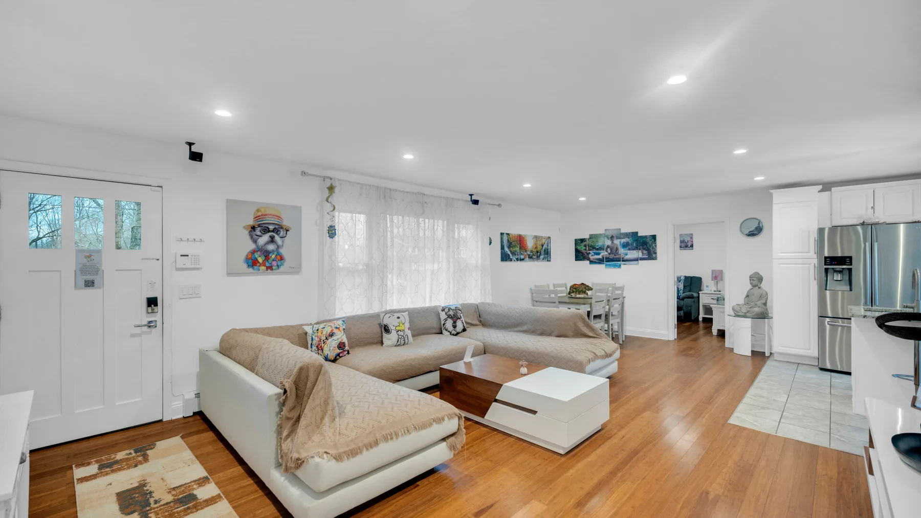 Una sala de estar y cocina diáfanas con asientos seccionales y suelo de madera.