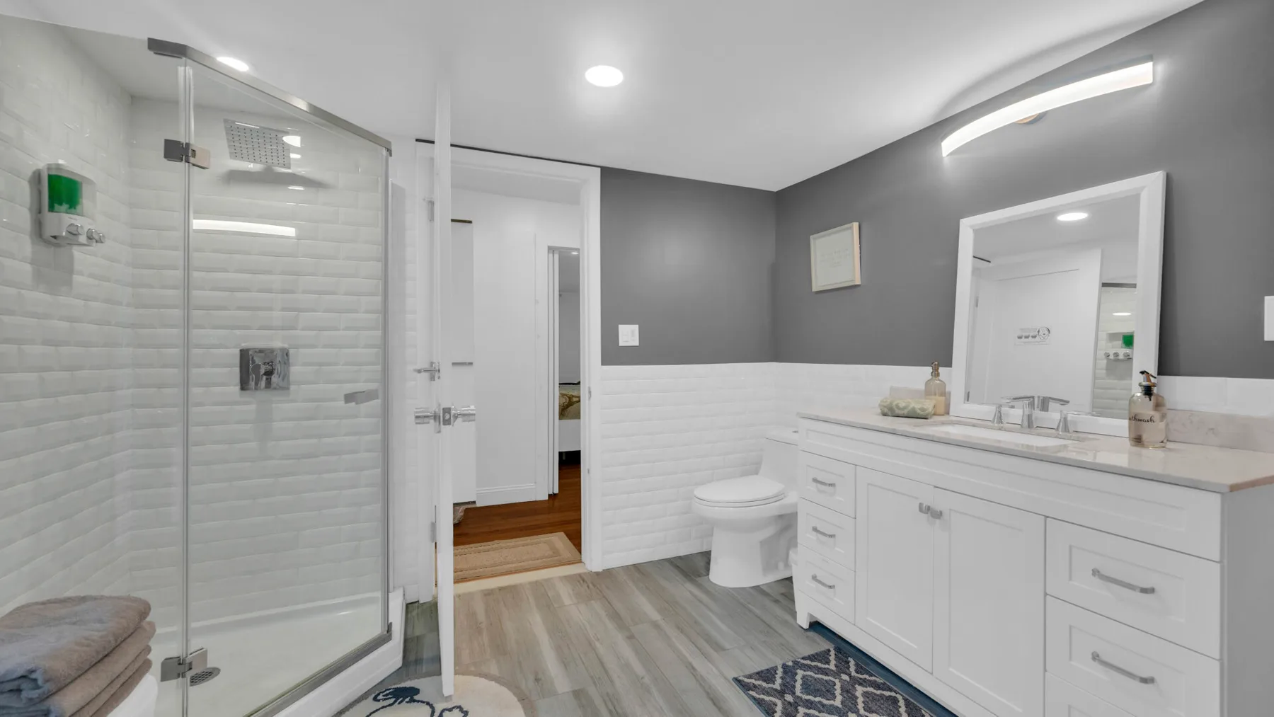 Un baño moderno con ducha de cristal, inodoro y un largo tocador.