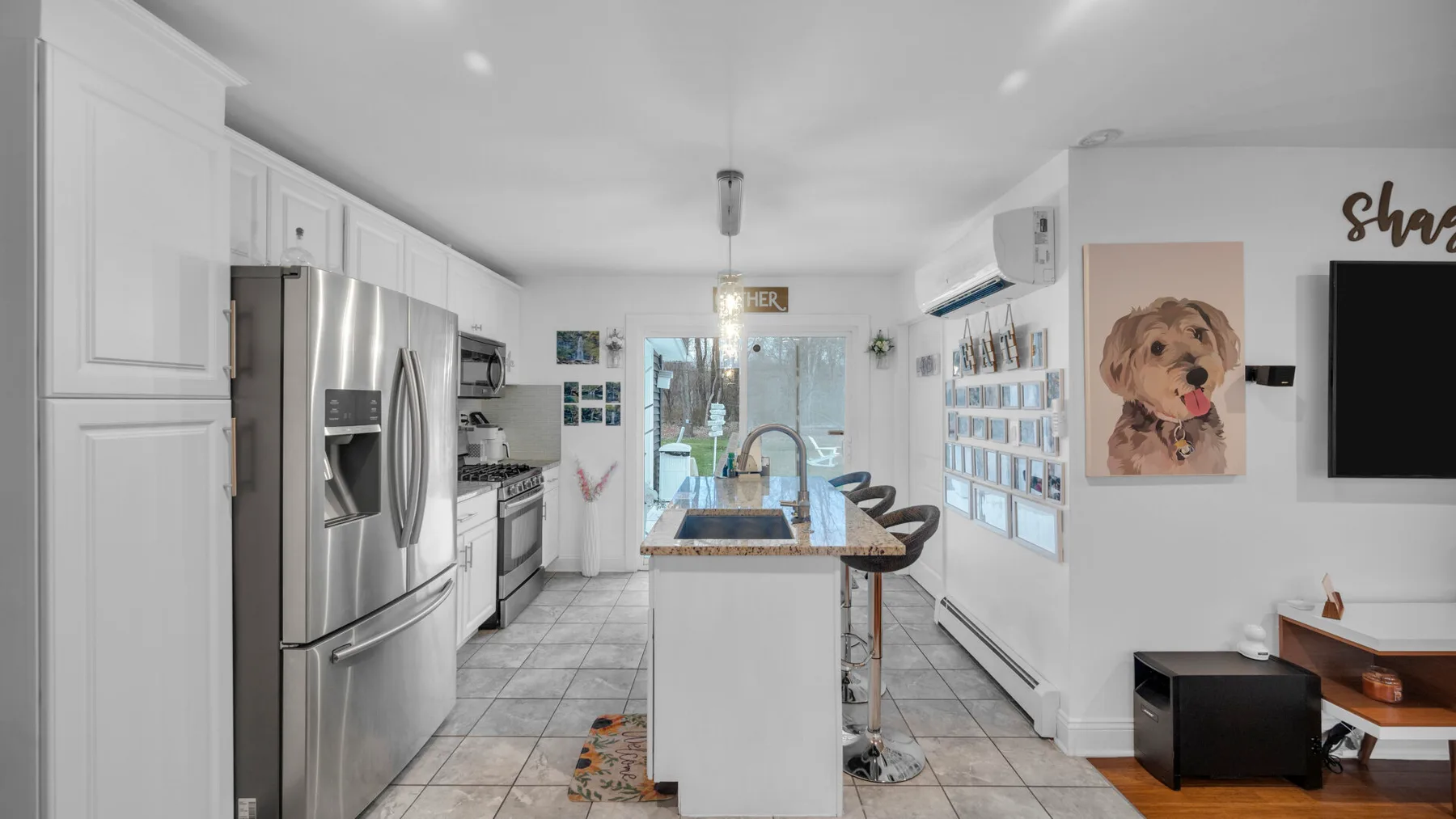 Una cocina luminosa con una isla central, electrodomésticos de acero inoxidable y asientos de barra.