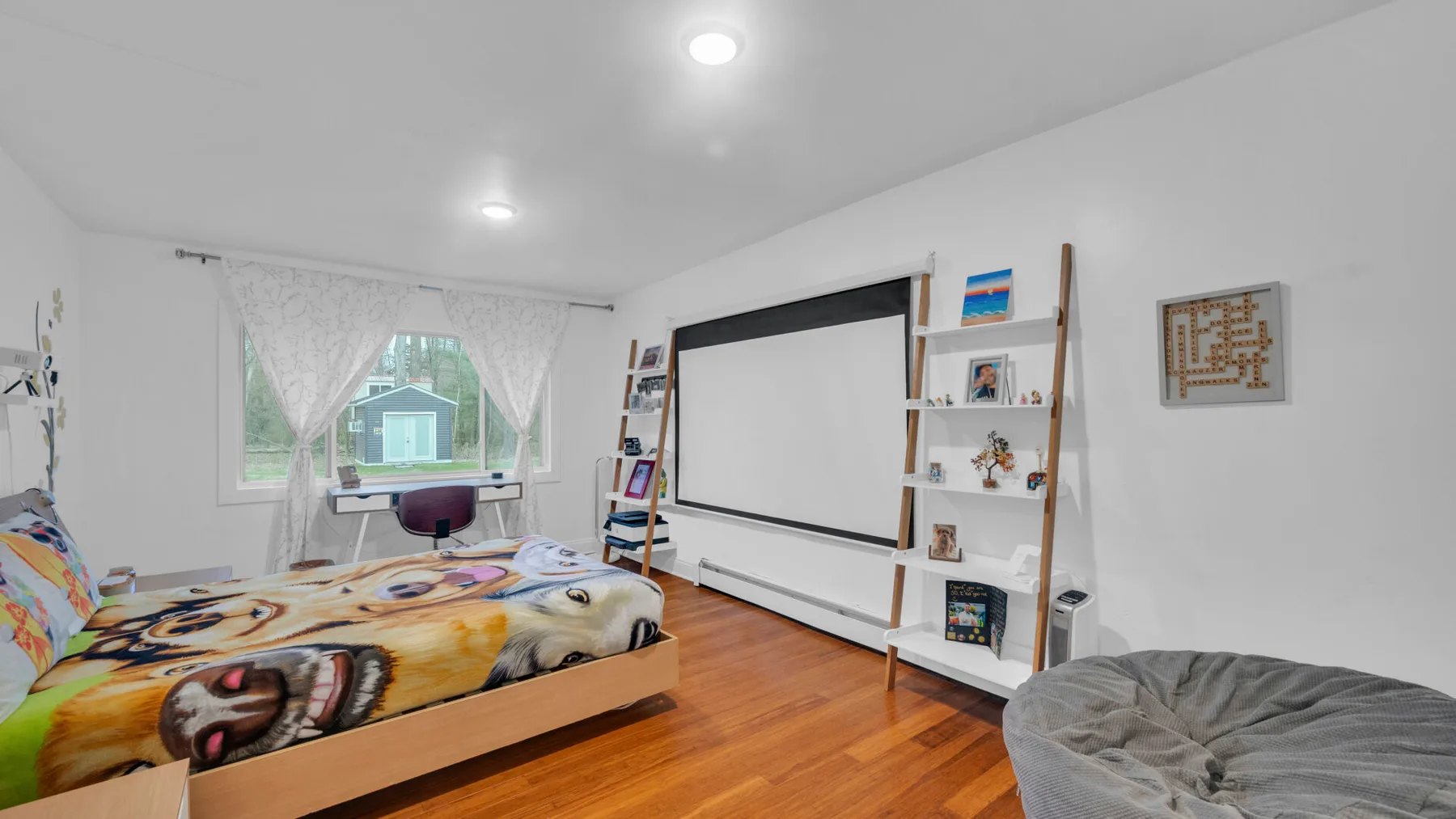 Un dormitorio con ropa de cama colorida, una ventana y una gran pantalla de proyección.