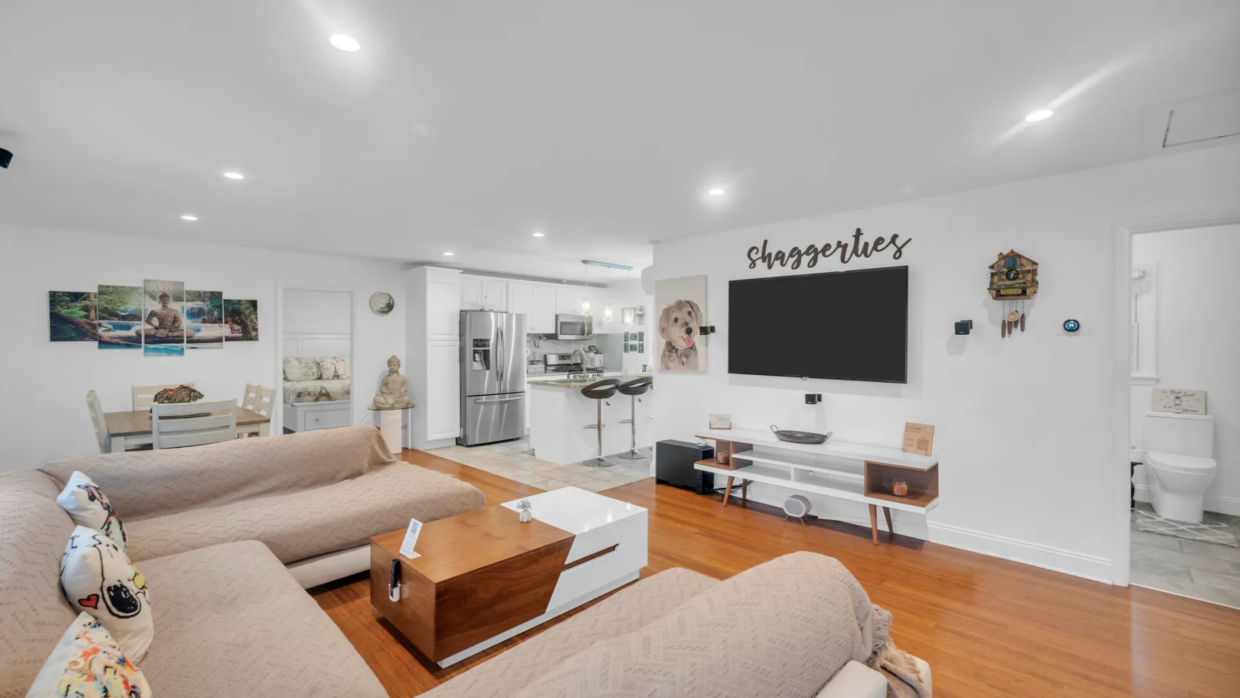 Una sala luminosa con asientos seccionales y un televisor sobre un mueble bajo.