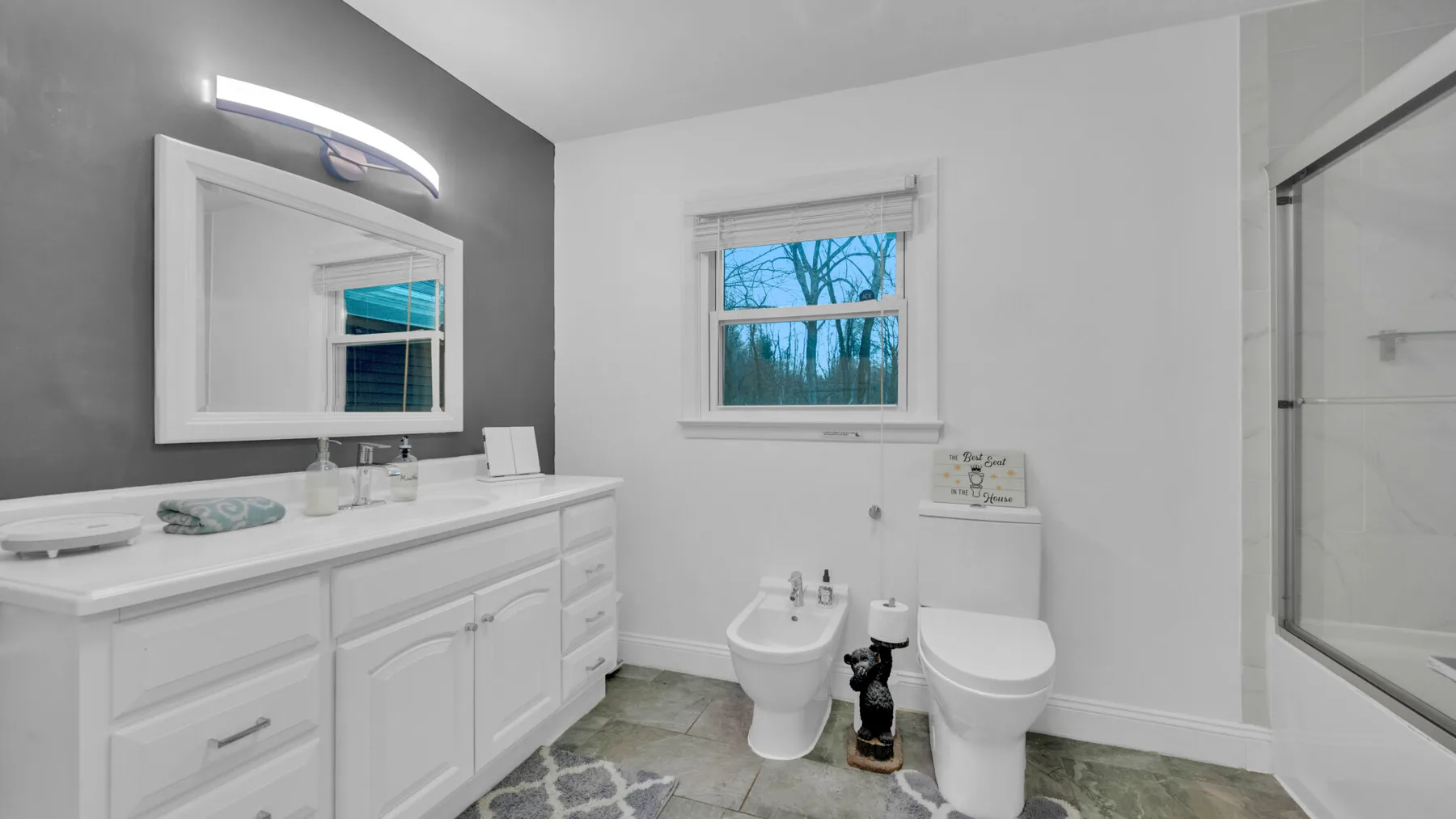Un baño luminoso con lavabo, inodoro, bidé y ducha.