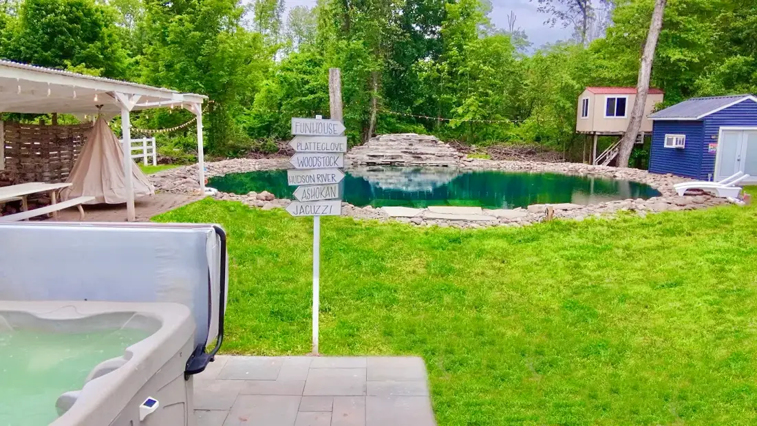 Zona de piscina al aire libre con una bañera de hidromasaje junto al césped.