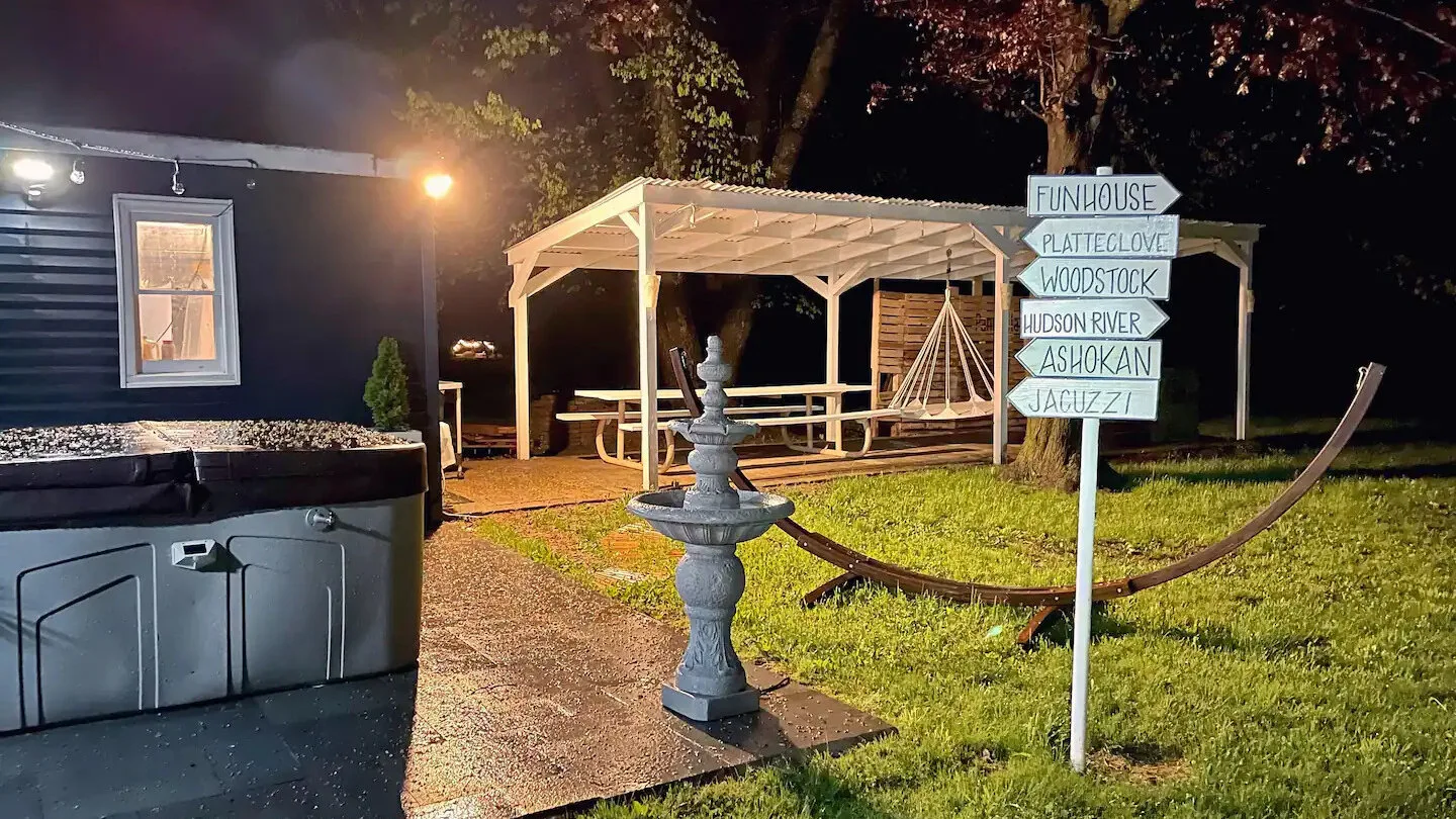 Un patio exterior de noche cuenta con una zona cubierta para sentarse y una pequeña fuente.