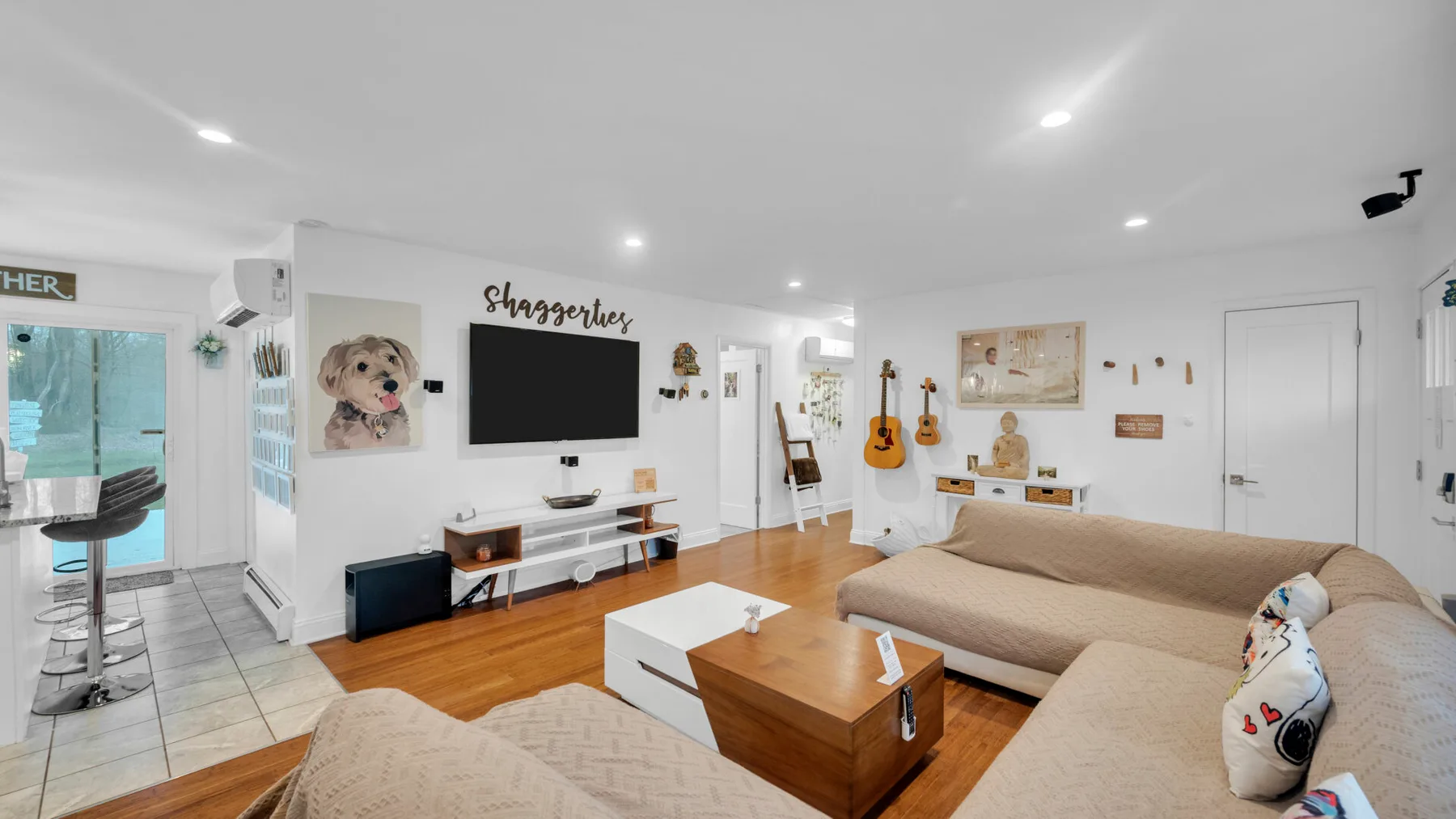 Una sala luminosa con asientos beige, una mesa de centro de madera y un televisor.