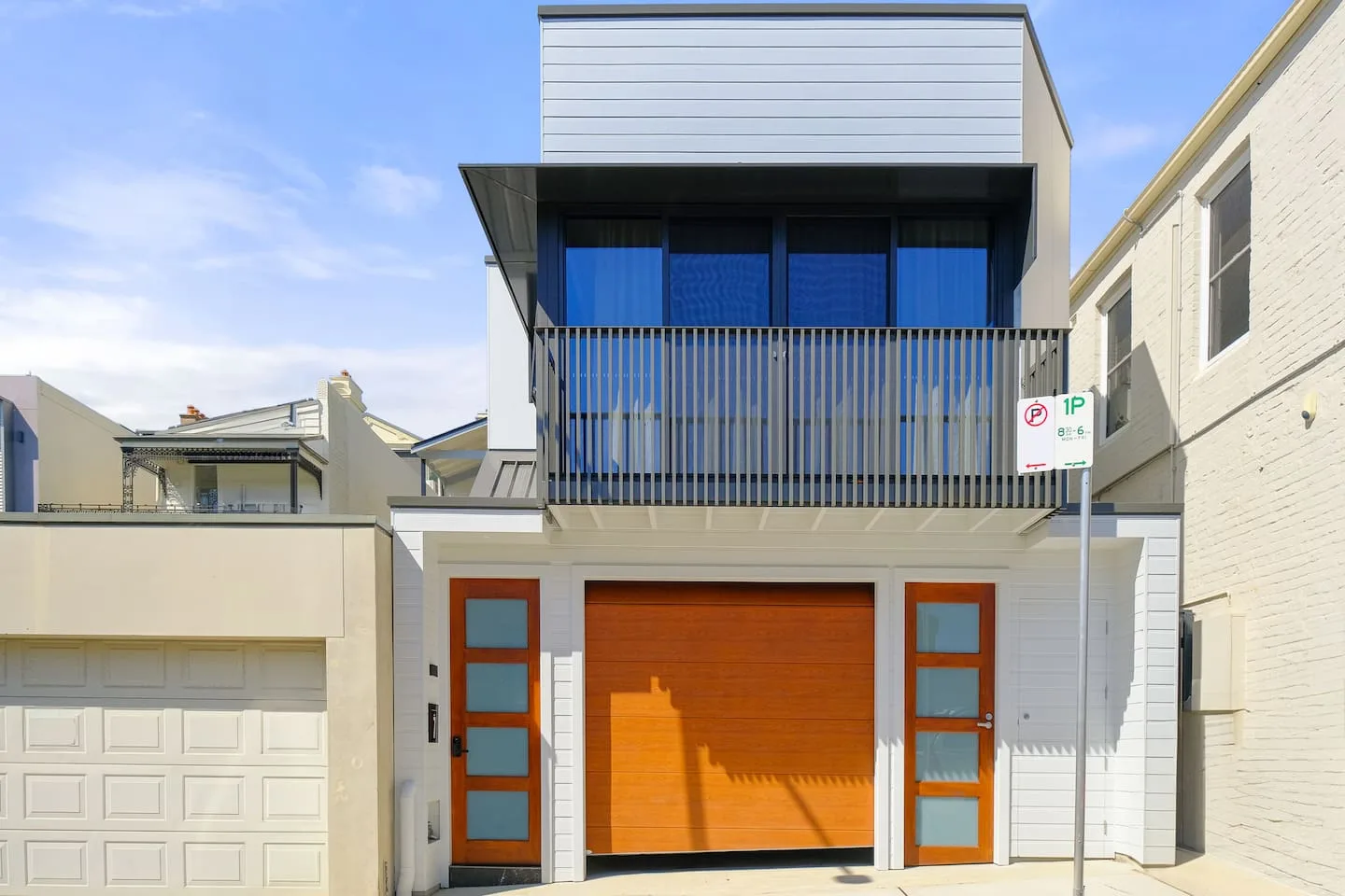 A modern house facade features a large orange garage door and matching entry doors.