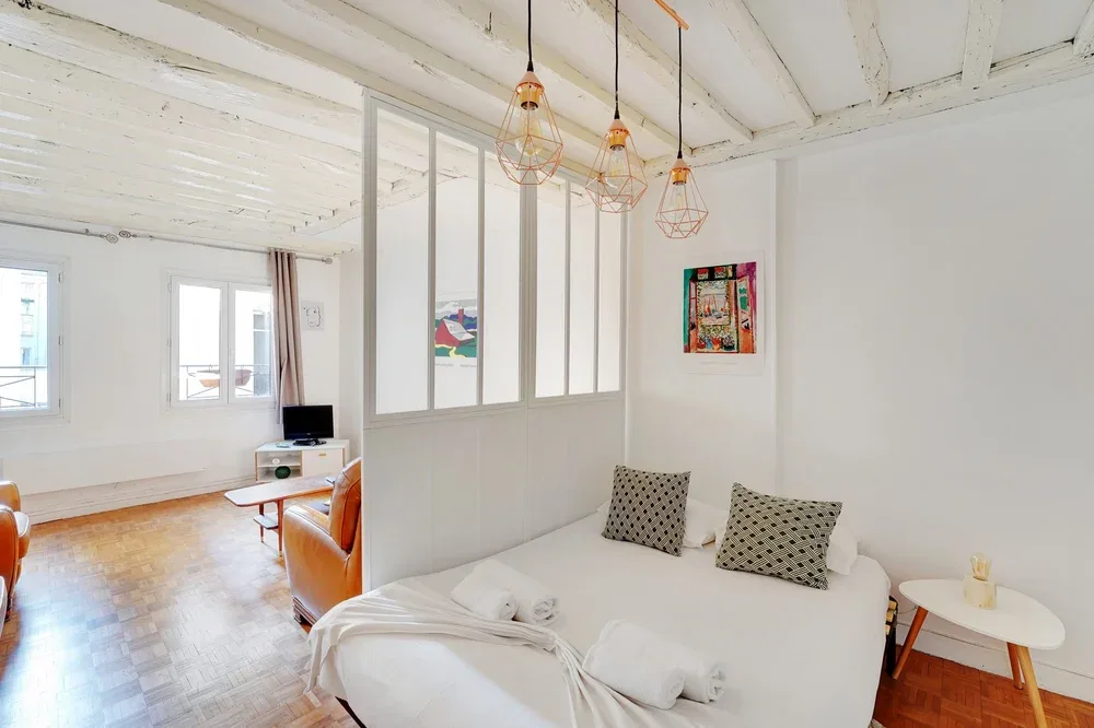 A bright living room with a white seating area and large windows.