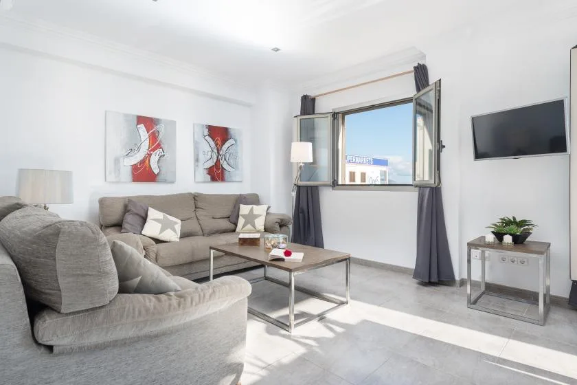 A bright living room with a sectional seating area and an open window.